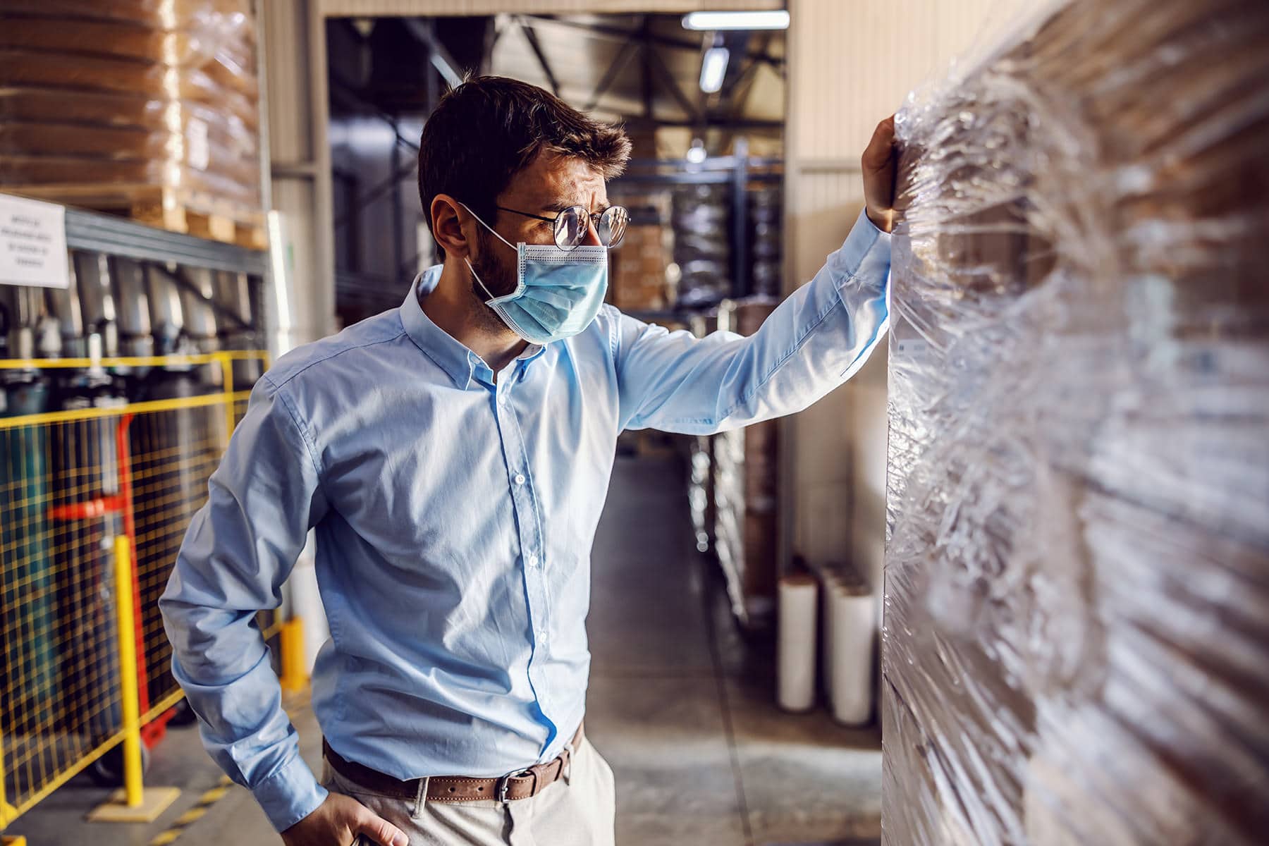 A man in a protective face mask inspecting a package.